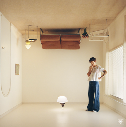 The song cover photo to Harry Styles' "As it Was". Harry Styles is standing in a plain, upside down room with his hand under his chin. 